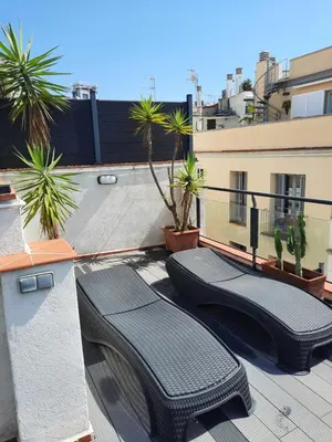 two black wicker benches on a balcony with palm trees at Apartaco Apartamentos in Sitges