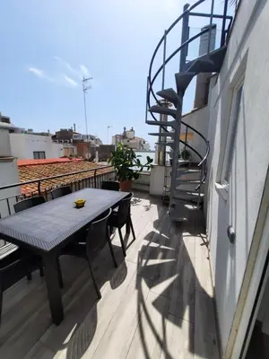 a table and chairs on a balcony with a staircase at Apartaco Apartamentos in Sitges