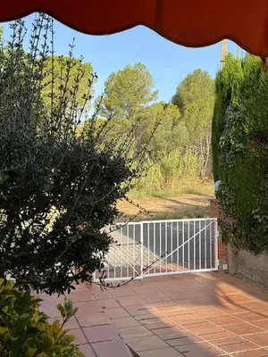 a gate on a walkway with bushes and trees at Casa acogedora al pie de Montserrat in Collbató