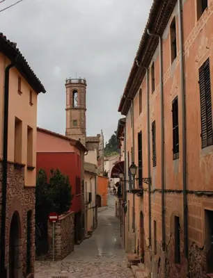 an alley with a clock tower in a town at Casa acogedora al pie de Montserrat in Collbató