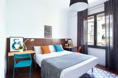 a bedroom with a bed and a desk with a blue chair at Traveller House in Barcelona