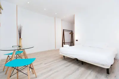 a bedroom with a bed and a table and a chair at Cathedral Apartments in Barcelona