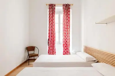 a room with two beds and a window with red curtains at BELLAFILA GOTHIC in Barcelona