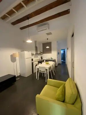 a living room with a yellow couch and a kitchen at Esparteria 2 in Barcelona