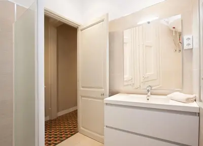 a white bathroom with a sink and a mirror at AB Bailen Apartments in Barcelona