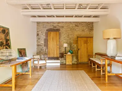 a living room with wooden furniture and a stone wall at Les Canes in Aiguafreda