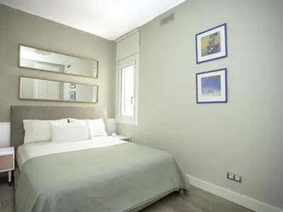 a white bedroom with a bed and a mirror at Sitges Spaces Bonaire Penthouse in Sitges