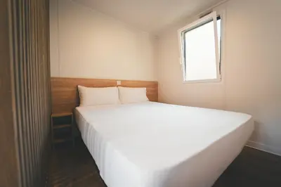 a white bed in a small room with a window at Tres Estrellas Barcelona by HolaCamp in Gavà