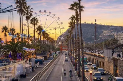 a city with a ferris wheel and a street with cars at Colom Apartment 3BR with Balcony & Port Vell Views in Barcelona
