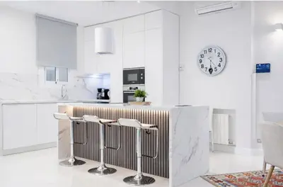 a kitchen with white walls and a counter with stools at Colom Apartment 3BR with Balcony & Port Vell Views in Barcelona
