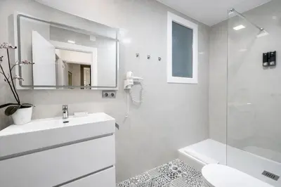 a white bathroom with a sink and a mirror at Colom Apartment 3BR with Balcony & Port Vell Views in Barcelona