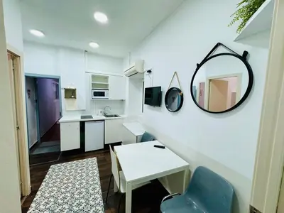 a small white kitchen with a mirror and a table at 028 Apartament 2 2 in Barcelona