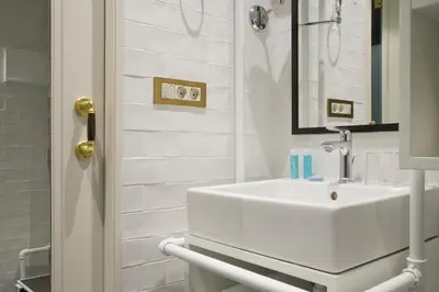 a white bathroom with a sink and a mirror at Praktik Bakery in Barcelona