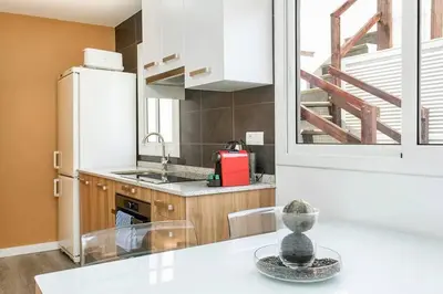 a kitchen with a refrigerator and a table with chairs at Cozy&new With Terrace in Hospitalet de Llobregat