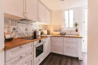 a white kitchen with white cabinets and wooden floors at Stylish 2 Bdr In Trendy Gracia in Barcelona