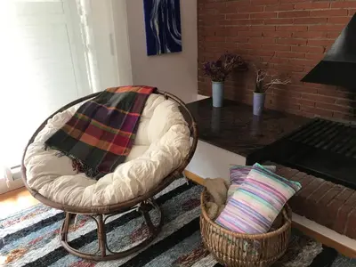 a living room with a chair with a pillow and a table at Gran apartamento de 4 habitaciones en Sitges in Sitges