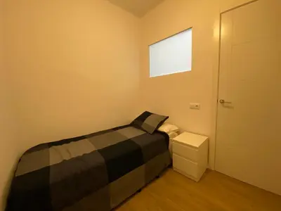 a small bedroom with a bed and a door at Casa adosada a 20 min centro de Barcelona in Hospitalet de Llobregat