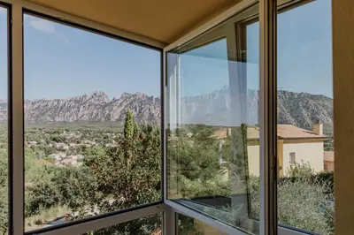 a room with windows with mountains in the background at Collbato Resort. in Collbató