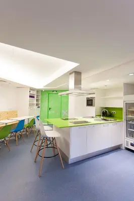 a kitchen with white cabinets and green accents at Dream Cube Hostel in Barcelona