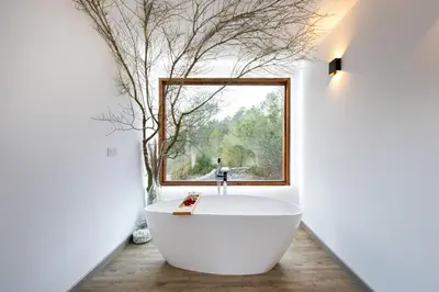 a bathroom with a large white tub in front of a window at Cabaña del Bosque in Canyelles