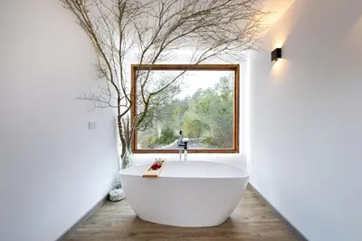 a bathroom with a large tub in front of a window at Cabaña del Bosque in Canyelles