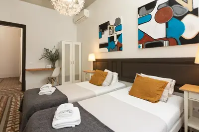 two beds in a room with paintings on the wall at Casa Maca Guest House in Barcelona