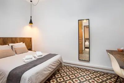 a bedroom with a bed with a mirror and a chair at Casa Maca Guest House in Barcelona