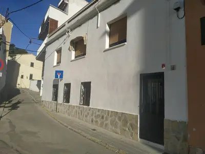 a white building with boarded up windows on a street at Casa turística Cunit in Cunit
