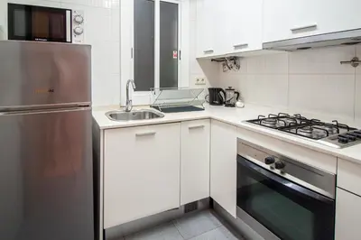 a kitchen with white cabinets and a stainless steel refrigerator at Apartamento zona Sagrada Familia in Barcelona