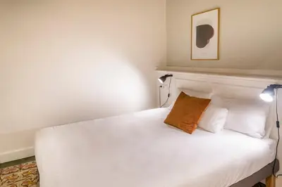 a bedroom with a white bed with a brown pillow at Casa Cosi - Putxet 3 in Barcelona