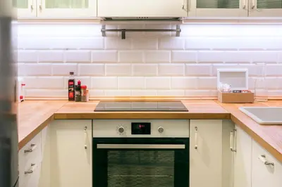 a kitchen with white cabinets and a stove top oven at Casa Cosi - Putxet 3 in Barcelona