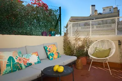 a couch and a chair on a patio with plants at Casa Cosi - Terrace 2 in Barcelona