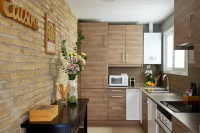 a kitchen with wooden cabinets and a brick wall at Casa Cosi - Casanova 1 in Barcelona