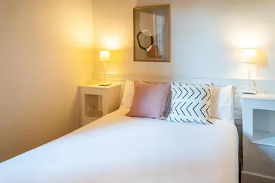 a bedroom with a bed with white sheets and pillows at Casa Cosi - Putxet 1 in Barcelona