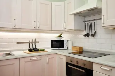 a kitchen with white cabinets and a microwave at Casa Cosi - Sant Gervasi 2 in Barcelona