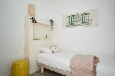 a small bedroom with a bed and a yellow stool at Casa Cosi - Francoli 4 in Barcelona