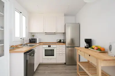 a kitchen with white cabinets and a stainless steel refrigerator at Casa Cosi - Francoli 4 in Barcelona