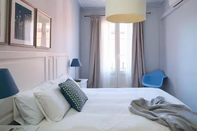 a bedroom with a white bed and a blue chair at Casa Cosi - El Farro 2 in Barcelona