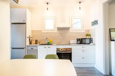 a kitchen with white cabinets and a table and chairs at Casa Cosi - La Gleva 3 in Barcelona