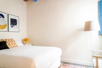 a white bedroom with a bed and a lamp at Casa Cosi - La Gleva 4 in Barcelona