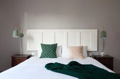 a bedroom with a white bed with green sheets and pillows at Casa Cosi - Casanova 7 in Barcelona