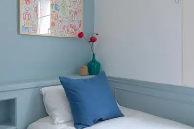a blue pillow and a vase with a flower on a couch at Casa Cosi - El Farro 1 in Barcelona