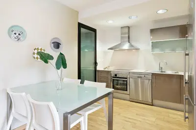 a kitchen with a glass table and white chairs at Sardenya Apartment by Olala Homes in Barcelona