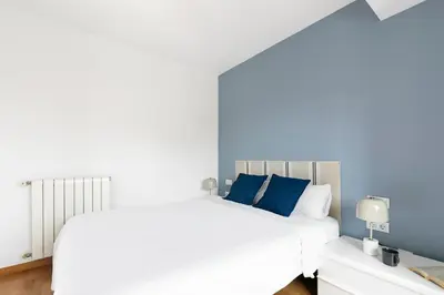 a bedroom with a white bed and blue pillows at Sardenya Apartment by Olala Homes in Barcelona