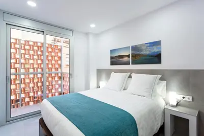 a bedroom with a large bed and two windows at 8 lacus in Hospitalet de Llobregat