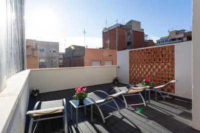 a balcony with chairs and tables on a roof at 8 lacus BAIKAL in Hospitalet de Llobregat