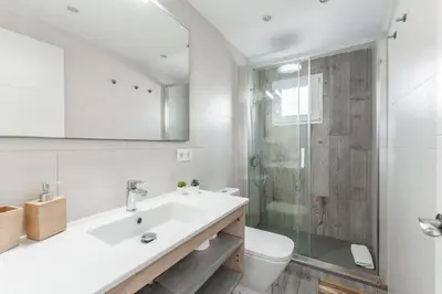 a white bathroom with a sink and a shower at Feel Welcome Barcelona Smart flat in Cornellà de Llobregat
