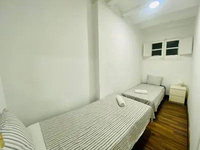 two beds in a room with white walls and wooden floors at 08 Apartament lof 3 2 in Barcelona