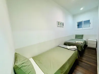 two beds in a small room with green sheets at 08 Apartament lof 3 2 in Barcelona
