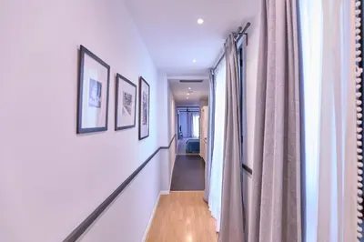 a hallway with white walls and a long hallway with pictures at Liceu Apartments by gaiarooms in Barcelona